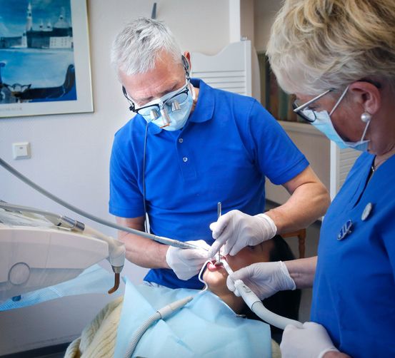 Tannlege Lars Hekneby arbeider med pasient, og assistent Eva hjelper til